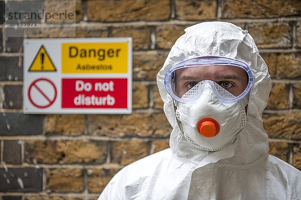 MODELL FREIGEGEBEN. Schutz vor Asbest. Der Arbeiter trägt Schutzkleidung  eine Gesichtsmaske und eine Schutzbrille Asbestschutz