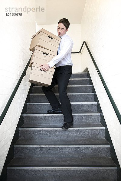 MODELL FREIGEGEBEN. Kisten tragen. Büroangestellter trägt Kisten die Treppe hinunter Kisten tragen