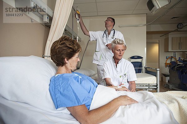 MODELL FREIGEGEBEN. Krankenschwestern bereiten einen Patienten für einen IV-Anschluss vor Krankenschwestern bereiten einen Patienten für einen IV-Anschluss vor