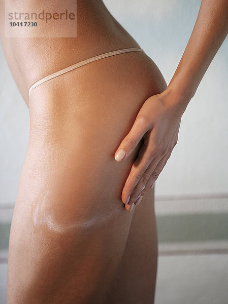 Frau  die eine Anti-Cellulite-Feuchtigkeitscreme auf ihren Po aufträgt