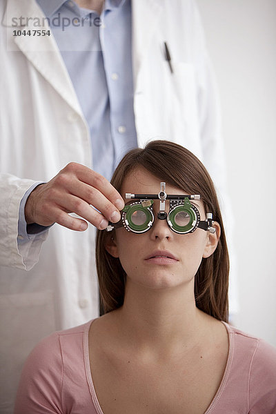 ein Optiker prüft die Augen einer jungen Frau