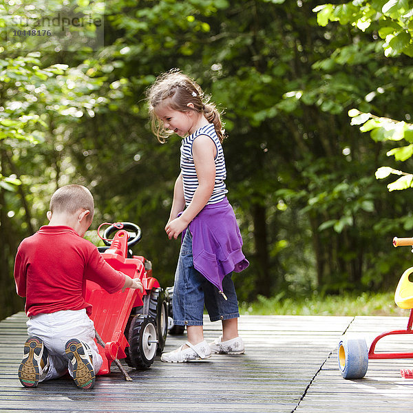 zwei Kinder spielen mit einem Spielzeugauto