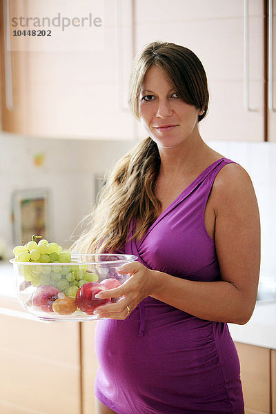 schwangere Frau mit einer Schale Obst