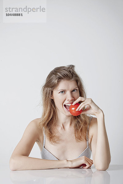 Frau beißt in eine Tomate