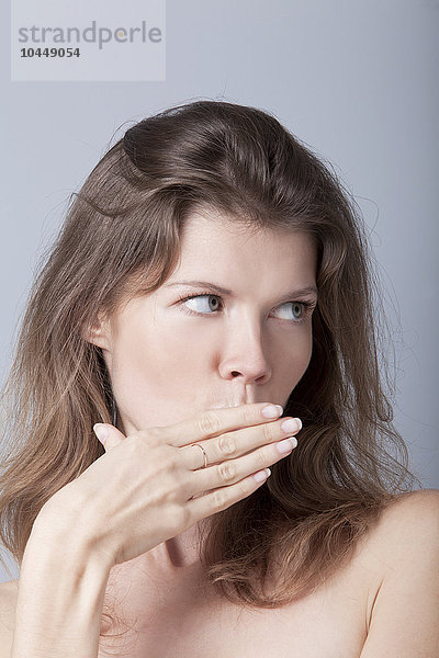 Frau bedeckt ihren Mund mit ihrer Hand