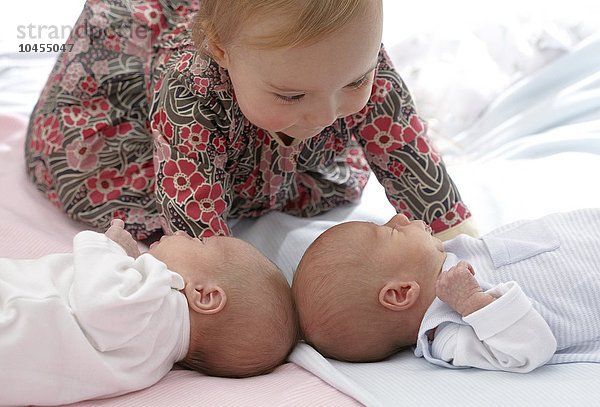 MODELL FREIGEGEBEN. Einjähriges Mädchen mit ihren zwei Wochen alten zweieiigen Zwillingsgeschwistern Einjähriges Mädchen mit kleinen Zwillingsgeschwistern