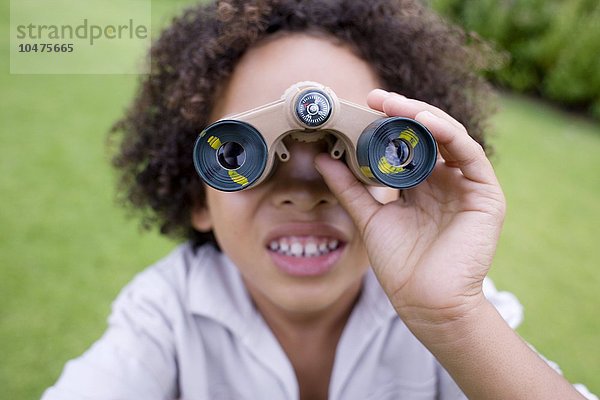 MODELL FREIGEGEBEN. Junge mit Fernglas in einem Park. Ferngläser enthalten Vergrößerungslinsen  die zum Betrachten entfernter Objekte verwendet werden.