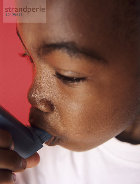 MODELL FREIGEGEBEN. Asthmatischer Junge bei der Verwendung seines Inhalators. Asthma ist eine Erkrankung  bei der sich die kleinen Atemwege (^Ibronchiolen^i) in der Lunge verengen und das Atmen erschweren. Dies führt zu Keuchen  Husten und Atemnot. Der Inhalator ist eine Aerosolpumpe  die bronchienerweiternde Medikamente freisetzt  welche die Atemwege erweitern. Asthmaanfälle können durch Sport  allergische Reaktionen und kaltes Wetter ausgelöst werden. Asthma entwickelt sich in der Regel in der Kindheit und bessert sich  wenn der Patient reifer wird.