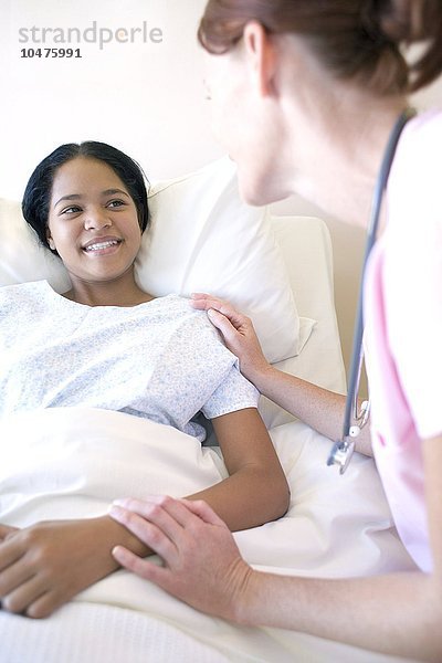 MODELL FREIGEGEBEN. Krankenschwester und Patientin. Krankenschwester  die ein jugendliches Mädchen auf einer Krankenhausstation untersucht Krankenschwester und Patientin