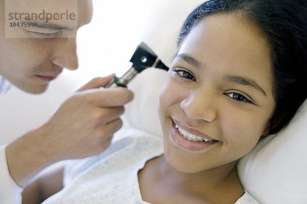 MODELL FREIGEGEBEN. Untersuchung des Ohrs. Arzt auf einer Station untersucht mit einem Otoskop das Ohr eines Mädchens Ohrenuntersuchung