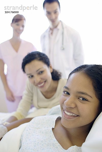 MODELL FREIGEGEBEN. Jugendlicher Patient im Krankenhaus. Teenager-Mädchen mit ihrer Mutter  Arzt und Krankenschwester auf einer Krankenhausstation Teenager-Krankenhaus-Patient