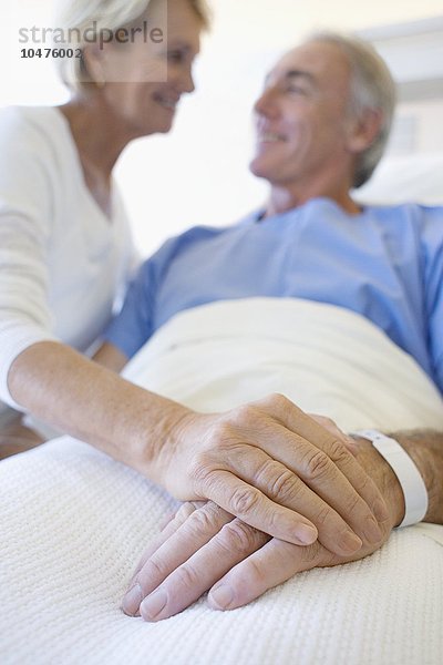 MODELL FREIGEGEBEN. Krankenhausbesuch. Frau hält die Hand ihres Partners bei einem Krankenhausbesuch Krankenhausbesuch