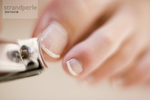 MODELL FREIGEGEBEN. Nägel kürzen. Frau schneidet ihre Zehennägel mit einem Nagelknipser Clipping nails