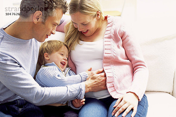 MODELL FREIGEGEBEN. Schwangere Frau und Familie. Vater und Sohn fühlen sich die Bewegungen ungeborenen Geschwister. Schwangere Frau und Familie