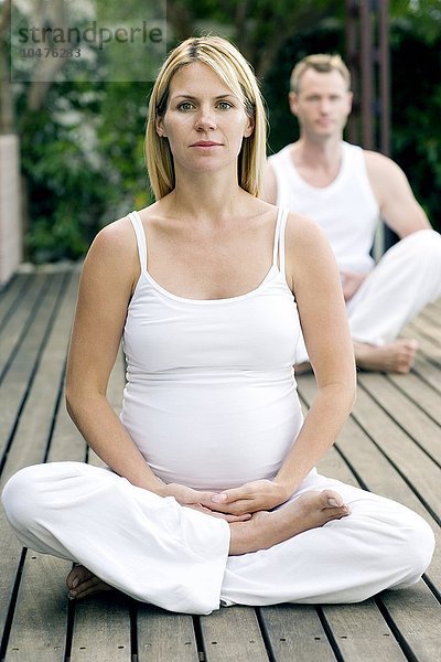 MODELL FREIGEGEBEN. Yoga in der Schwangerschaft. Schwangere Frau im dritten Trimester  die mit ihrem Partner Yoga-Übungen durchführt. Yoga in der Schwangerschaft