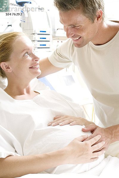 MODELL FREIGEGEBEN. Werdende Eltern. Schwangere Frau in einem Krankenhausbett  die ihren Partner ansieht Werdende Eltern
