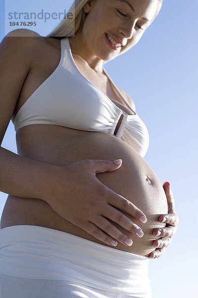 MODELL FREIGEGEBEN. Schwangere Frau blickt auf ihren geschwollenen Bauch Schwangere Frau