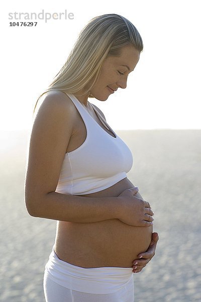 MODELL FREIGEGEBEN. Schwangere Frau blickt auf ihren geschwollenen Bauch Schwangere Frau