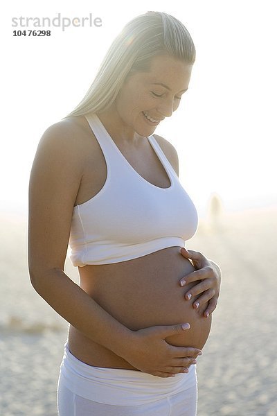 MODELL FREIGEGEBEN. Schwangere Frau blickt auf ihren geschwollenen Bauch Schwangere Frau