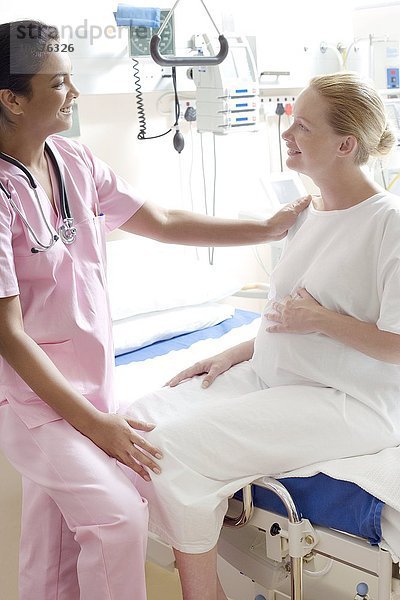 MODELL FREIGEGEBEN. Schwangerschaftsuntersuchung. Gynäkologe im Gespräch mit einer schwangeren Frau auf einer Entbindungsstation Schwangerschaftsuntersuchung