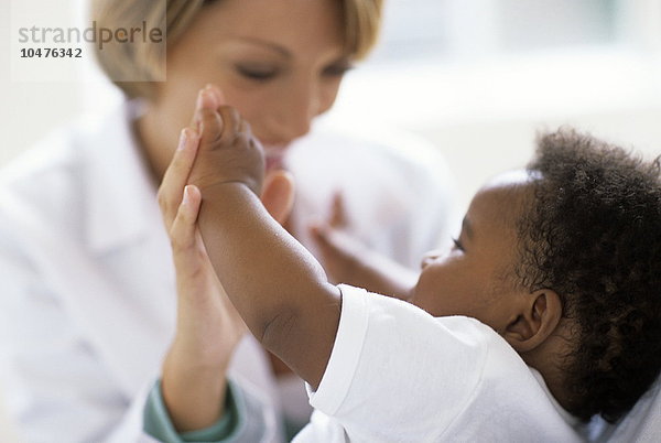 MODELL FREIGEGEBEN. Pädiatrische Untersuchung. Ein Arzt spielt mit einem 5 Monate alten Patienten während einer Untersuchung. Pädiatrische Untersuchung