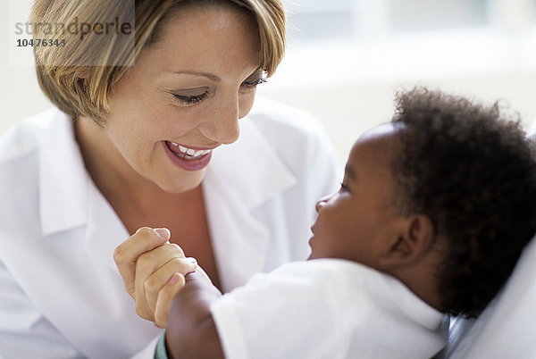 MODELL FREIGEGEBEN. Pädiatrische Untersuchung. Ärztin spielt während einer Untersuchung mit ihrem 5 Monate alten männlichen Patienten Pädiatrische Untersuchung
