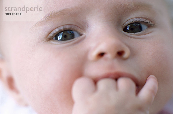 MODELL FREIGEGEBEN. Baby. Gesicht eines 4 Monate alten Mädchens mit der Hand im Mund Gesicht eines Mädchens