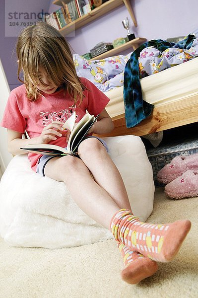 MODELL FREIGEGEBEN. Lesen in der Kindheit. Mädchen liest ein Buch in ihrem Schlafzimmer Kindheit Lesen