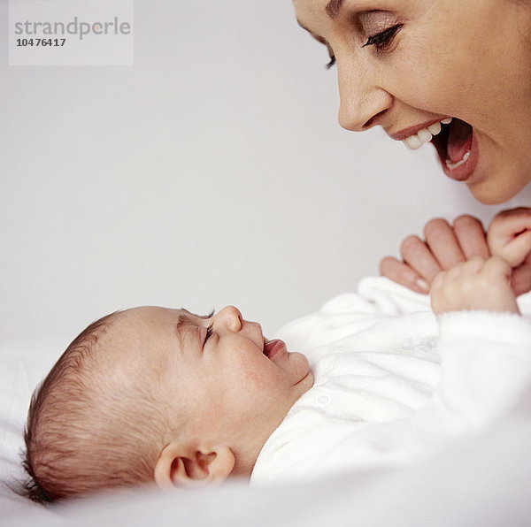 MODELL FREIGEGEBEN. Mutter und kleines Mädchen. Eine Mutter und ihr 12 Wochen altes Mädchen schauen sich lächelnd an. Babys erkennen menschliche Gesichter schon sehr früh und reagieren darauf. Mutter und kleines Mädchen