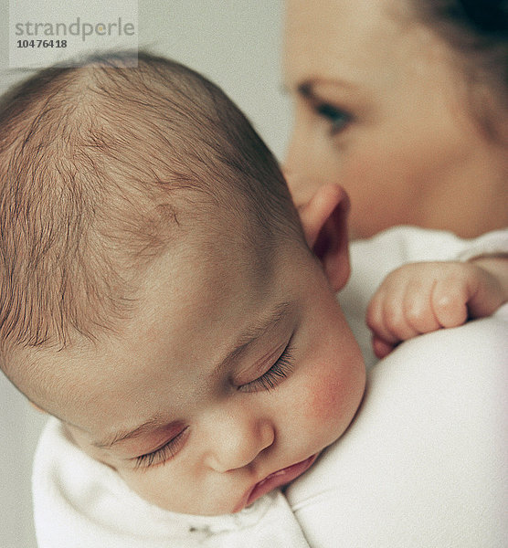 MODELL FREIGEGEBEN. Mutter und kleines Mädchen. Ein 12 Wochen altes Mädchen schläft auf der Schulter seiner Mutter Mutter und kleines Mädchen