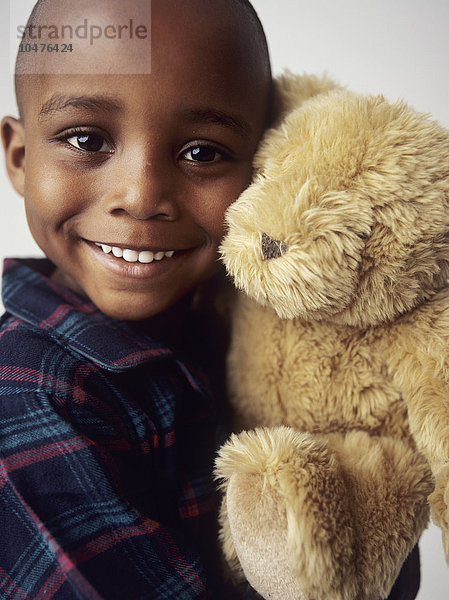 MODELL FREIGEGEBEN. Junge mit Teddybär. 4 Jahre alter Junge lächelt und hält einen Teddybär. Kuscheltiere können einem Kind Gesellschaft leisten und nachts nach einem Albtraum Trost spenden. Junge mit Teddybär