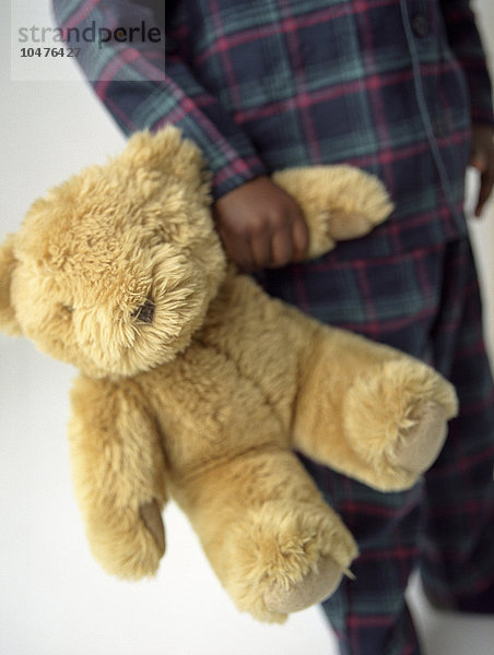 MODELL FREIGEGEBEN. Teddybär eines Jungen. Teddybär  der von einem 4-jährigen Jungen gehalten wird. Kuscheltiere können einem Kind Gesellschaft leisten und nachts nach einem Alptraum Trost spenden. Teddybär für Jungen