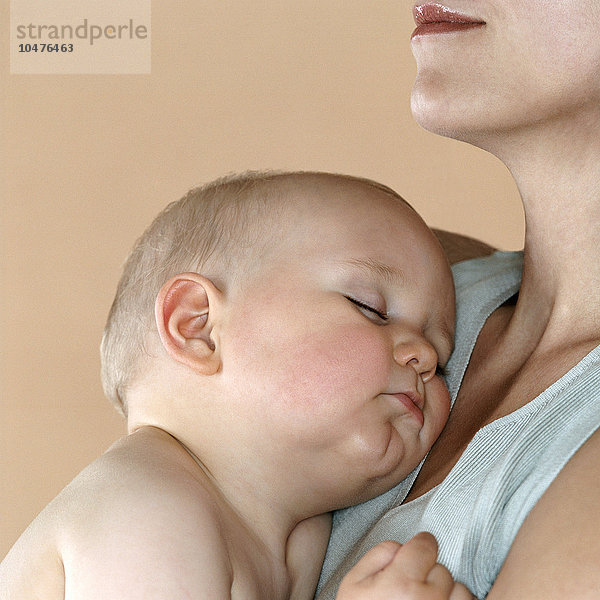 MODELL FREIGEGEBEN. Schlafendes Baby in den Armen seiner Mutter. Er ist neun Monate alt. Schlafendes Baby