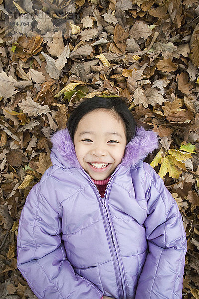MODELL FREIGEGEBEN. Lächelndes Mädchen auf Herbstblättern liegend Lächelndes Mädchen auf Herbstblättern liegend