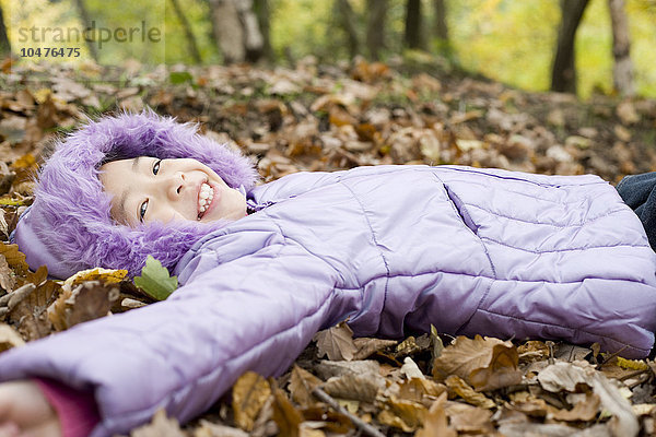 MODELL FREIGEGEBEN. Lächelndes Mädchen auf Herbstblättern liegend Lächelndes Mädchen auf Herbstblättern liegend