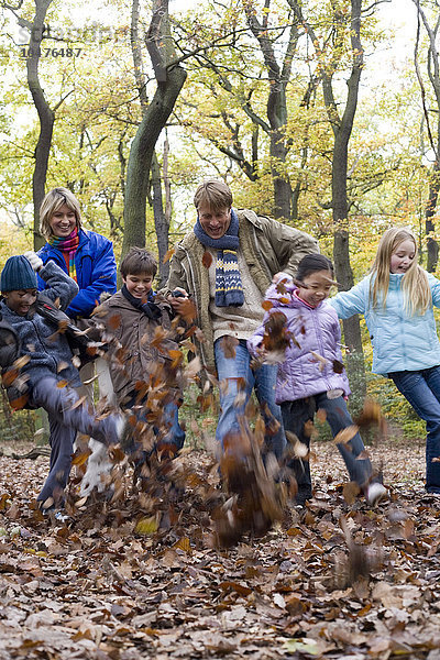 MODELL FREIGEGEBEN. Kicken Herbstblätter. Eltern und Kinder treten Blätter in einem Wald im Herbst Eltern und Kinder spielen in einem Wald
