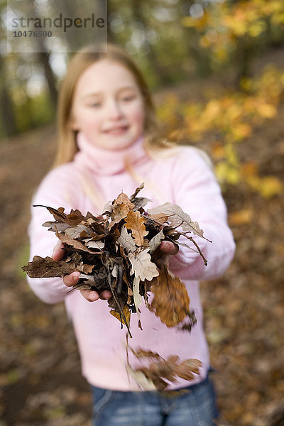 MODELL FREIGEGEBEN. Mädchen hält Herbstblätter in einem Wald Mädchen hält Herbstblätter