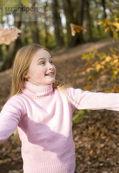MODELL FREIGEGEBEN. Mädchen spielt mit Herbstblättern in einem Wald Mädchen spielt mit Herbstblättern