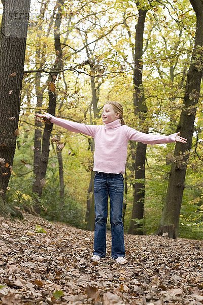 MODELL FREIGEGEBEN. Mädchen spielt mit Herbstblättern in einem Wald Mädchen spielt mit Herbstblättern