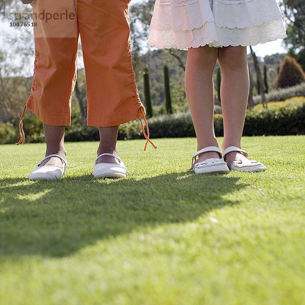 Beine von Mädchen. Zwei Mädchen stehen auf Gras Mädchenbeine