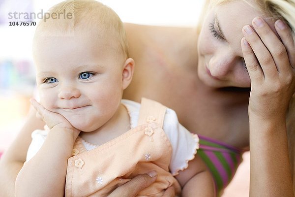 MODELL FREIGEGEBEN. Teenager-Mutter und Baby. Gestresste junge Mutter hält ihre 10 Monate alte Tochter. Posiert von Modellen Teenager-Mutter und Baby