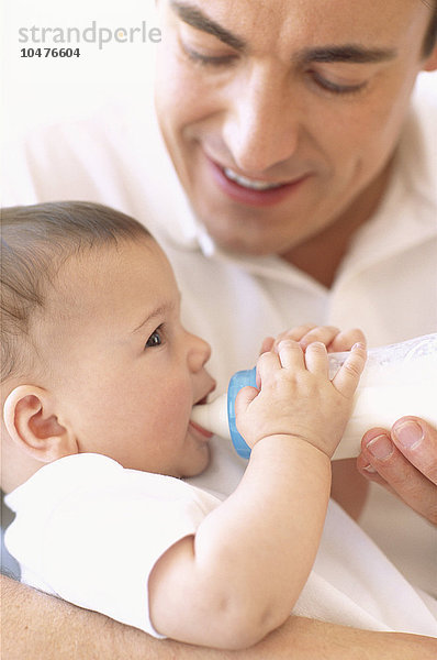 MODELL FREIGEGEBEN. Vater  der sein Baby mit der Flasche füttert. Vater füttert sein 5 Monate altes Mädchen mit der Flasche Vater füttert Baby mit der Flasche