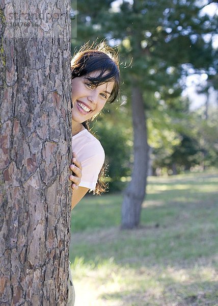 MODELL FREIGEGEBEN. Glückliche Frau  die hinter einem Baum hervorschaut Glückliche Frau