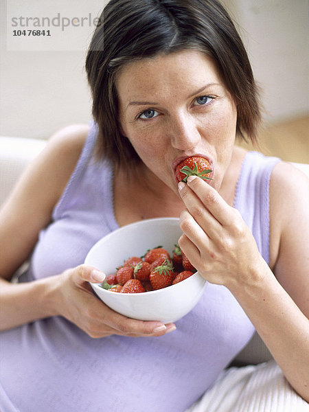 MODELL FREIGEGEBEN. Gesunde Ernährung. Frau isst Erdbeeren. Erdbeeren sind reich an Mineralien und Vitamin C und enthalten wenig Fett. Gesunde Ernährung