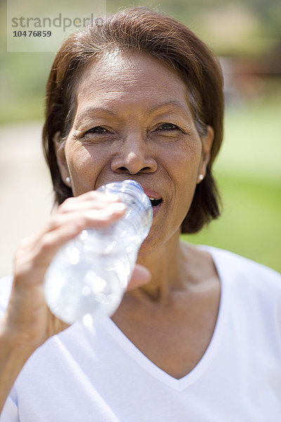 MODELL FREIGEGEBEN. Frau trinkt Wasser beim Sport. Durch das Schwitzen beim Sport geht Wasser verloren  und es ist wichtig  den Körper durch das Trinken von viel Wasser zu rehydrieren.