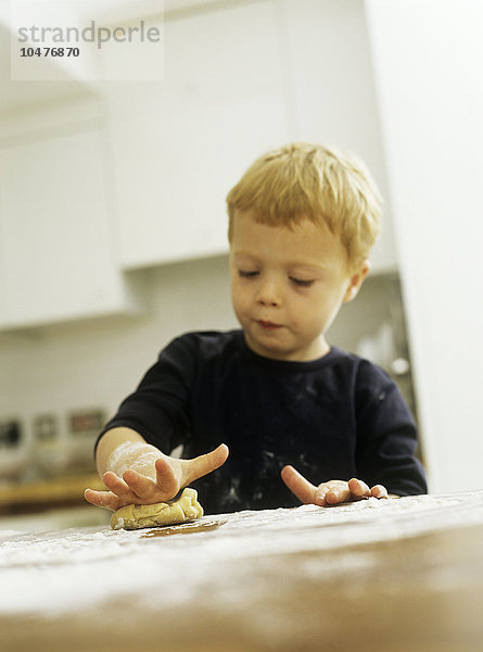 MODELL FREIGEGEBEN. Kekse backen. Dreijähriger Junge rollt einen Keksteig Kekse backen