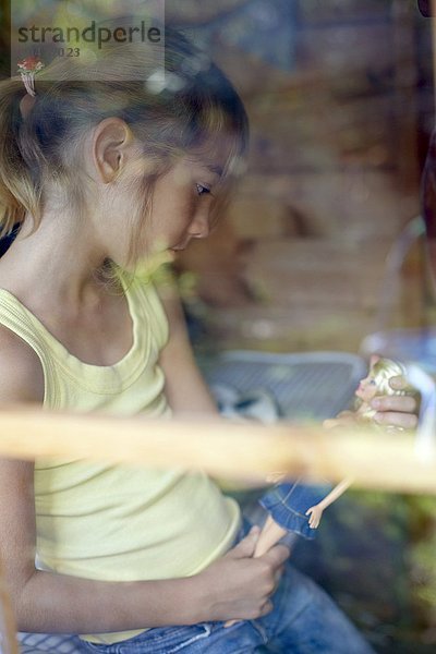 MODELL FREIGEGEBEN. Mädchen spielt in einem Wendy-Haus. Sie ist acht Jahre alt. Mädchen spielt in einem Wendy-Haus