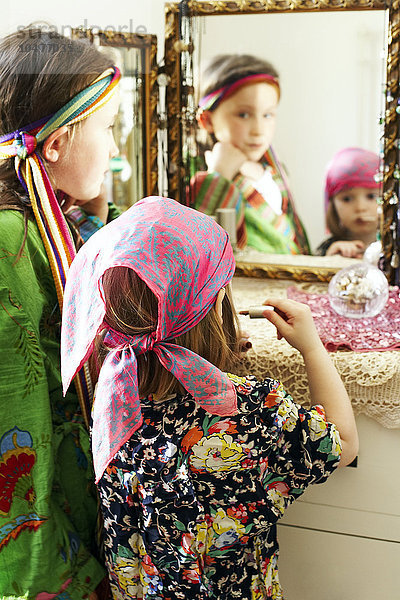 MODELL FREIGEGEBEN. Verkleiden. Vierjähriges Mädchen benutzt einen Spiegel  um Lippenstift während eines Verkleidungsspiels aufzutragen.