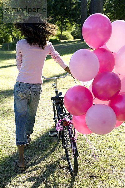 MODELL FREIGEGEBEN. Frau mit einem Fahrrad und Luftballons Frau mit einem Fahrrad und Luftballons