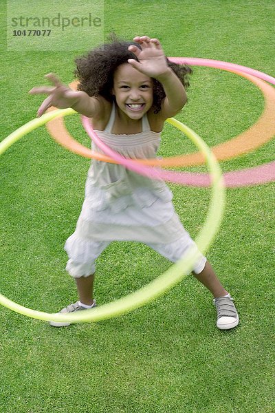 MODELL FREIGEGEBEN. Mädchen spielt mit Hula-Hoop-Reifen in einem Garten Mädchen spielt mit Hula-Hoop-Reifen